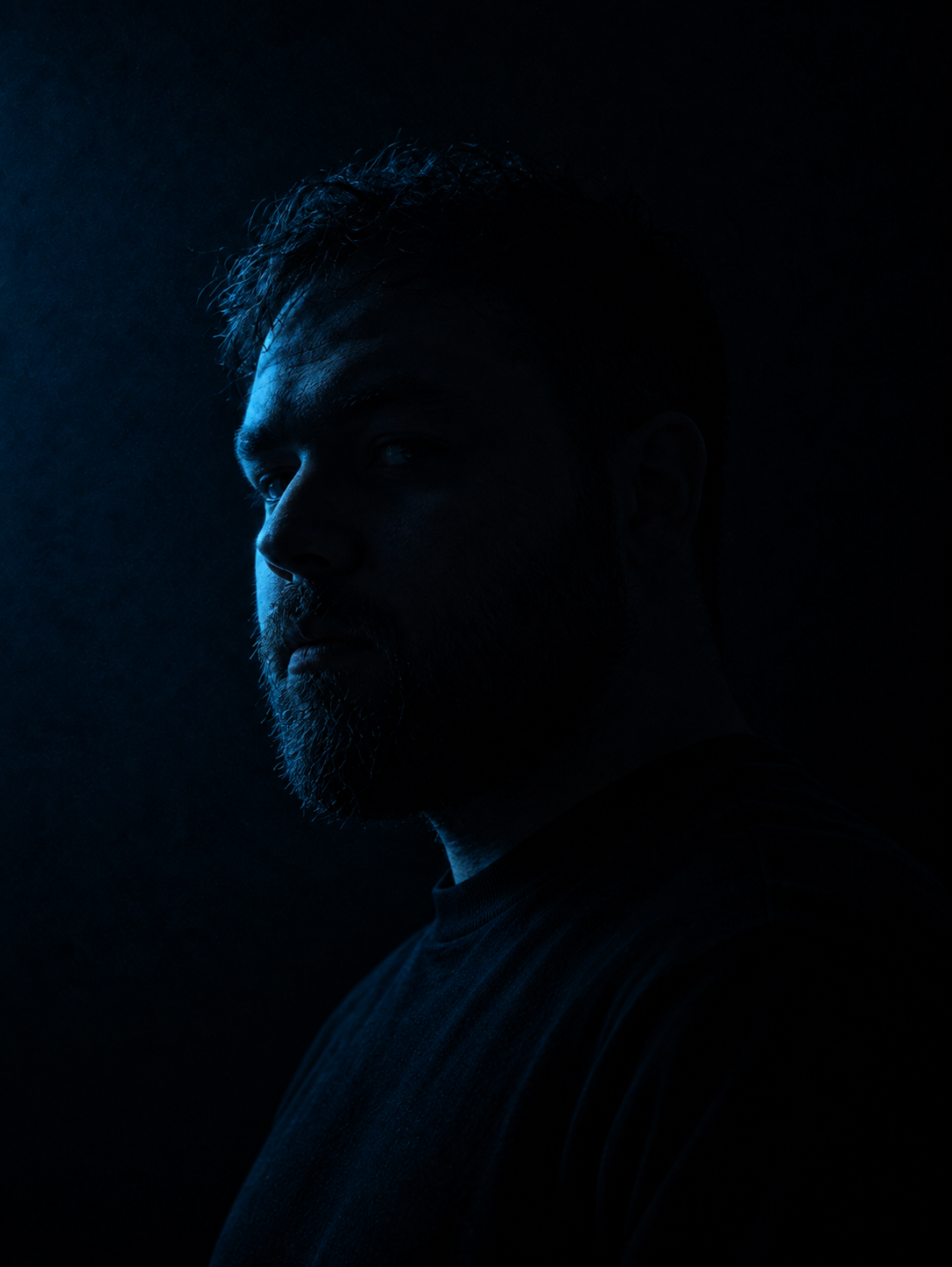 Portrait of Kaan Cenik lit in deep blue